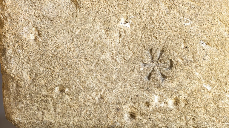 Carving of a small Christian symbol called a chi-rho, the first two letters of 'Christ' in the Greek alphabet
